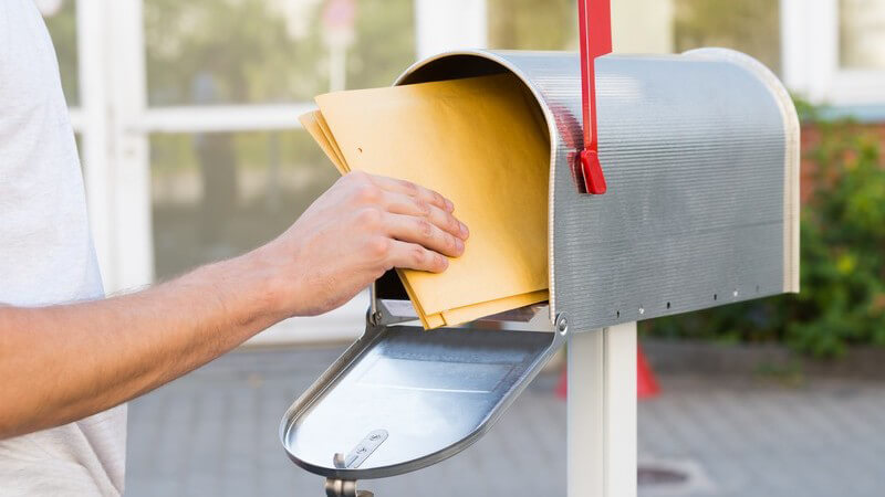 Mann nimmt die Post aus einem amerikanischen Briefkasten