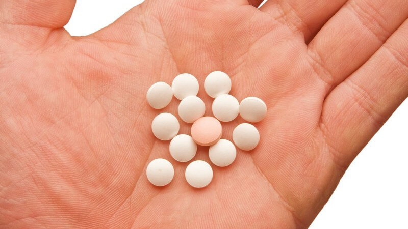 Mehrere Pillen auf Handfläche, weißer Hintergrund