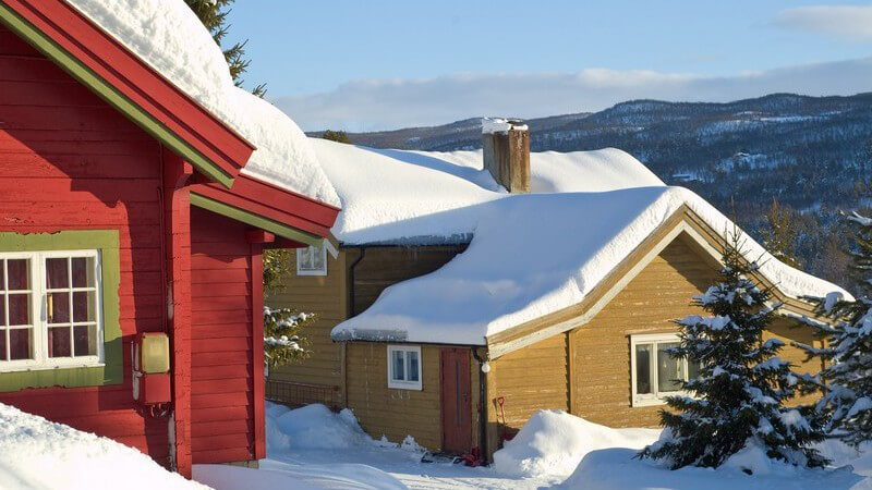 Dorf in Bergen, Schnee, Schneeschicht auf Häusern, bunte Blockhütten, Sonnenlicht