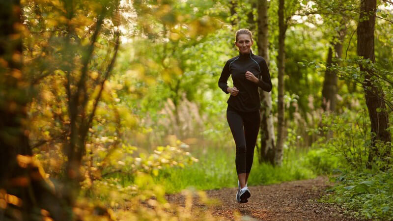 Junge Frau im Sportoutfit joggt durch den Wald