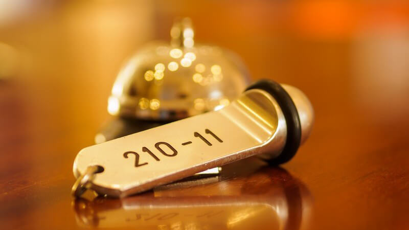 Hotelrezeption: Schlüssel mit Zimmernummer liegt vor Empfangsklingel