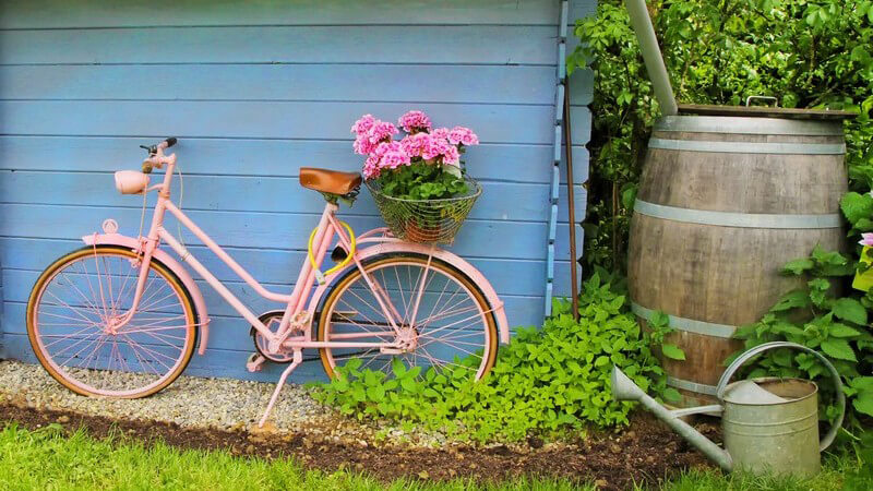 Rosa Damenrad steht vor einer blauen Holzhütte