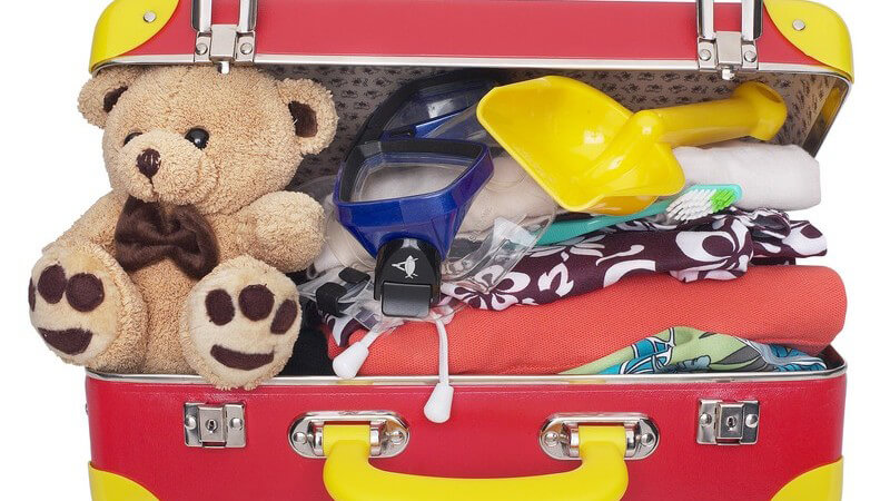 Gepackter Reisekoffer eines Kindes mit Teddybär, Strandspielzeug etc.
