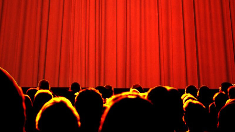 Rückansicht Köpfe einer großen Menge vor geschlossenem roten Vorhang, Kino, Theater