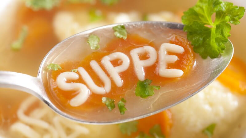 Klare Suppe mit Buchstaben-Nudeln, Wort "Suppe" auf Löffel