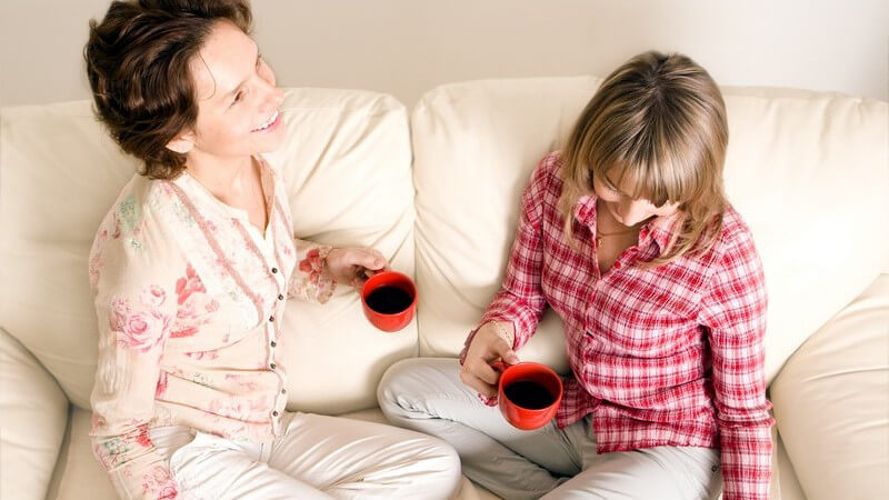Zwei Frauen sitzen mit Kaffee auf Couch