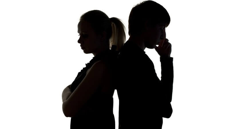 Silhuette von jungem Mann und Frau auf weißem Hintergrund, lehnen mit Rücken aneinander