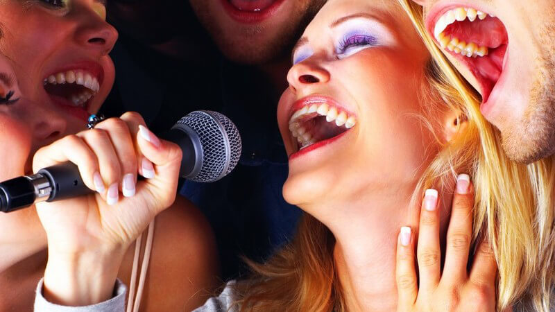Gruppe junger Menschen singt zusammen auf Karaoke Party