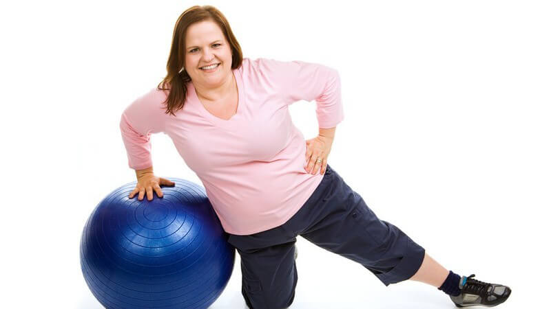 Übergewichtige Frau macht Übungen am Gymnastikball