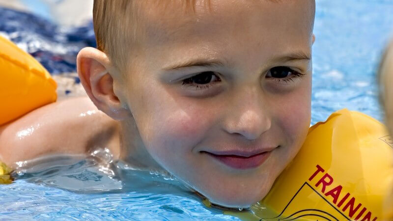 Kleiner Junge mit Schwimmflügeln im Schwimmbecken