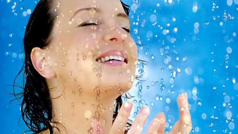 Junge Frau genießt Wasserstrahl in Dusche