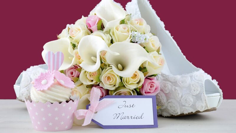 Weiße Brautschuhe mit Brautstrauß und rosa Cupcake