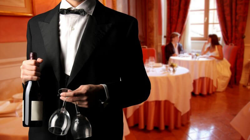 Körperausschnitt Kellner mit Weinflasche und zwei Gläsern im Restaurant