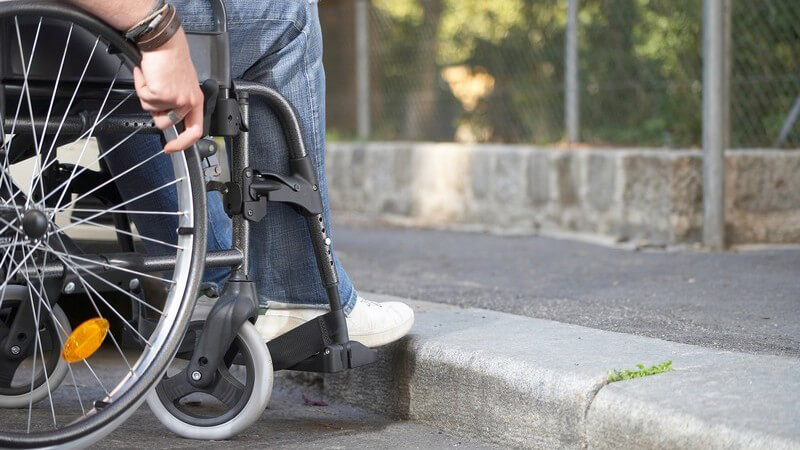 Nahaufnahme Rollstuhlfahrer vor Bordsteinkante