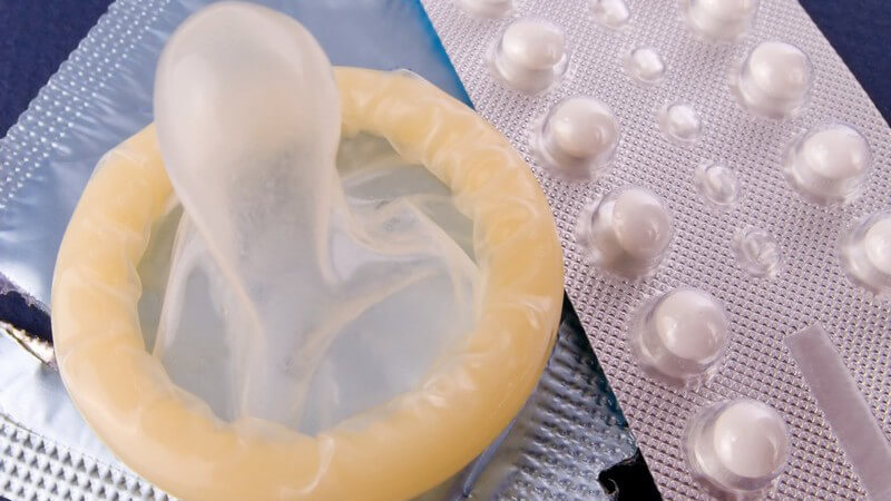 Nahaufnahme Antibabypillen, Kondom auf aufgerissener Packung