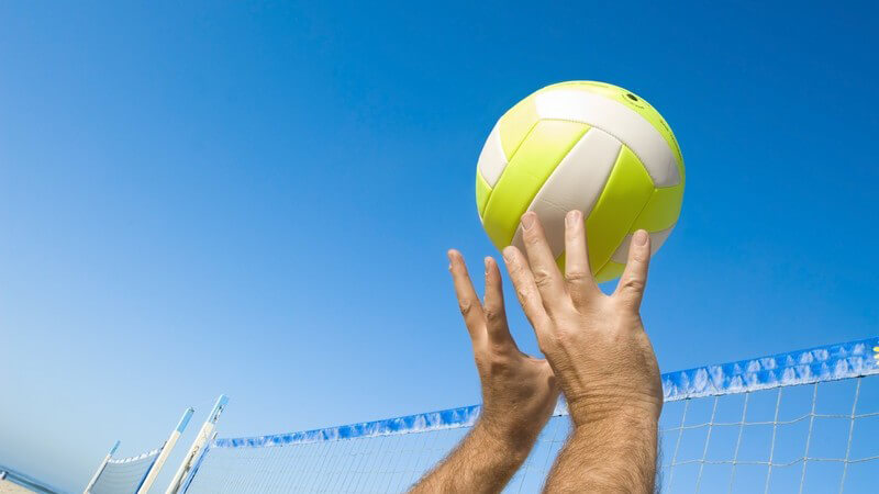 Nahaufnahme Volleyball wird übers Netz gebracht unter blauem Himmel