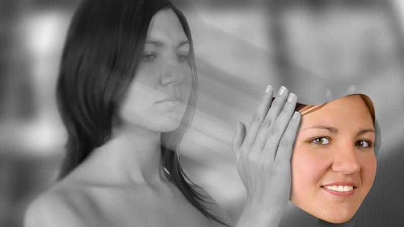 Schwarz-weiß Bild unglückliche Frau hält ihr glückliches Gesicht in bunt in den Händen