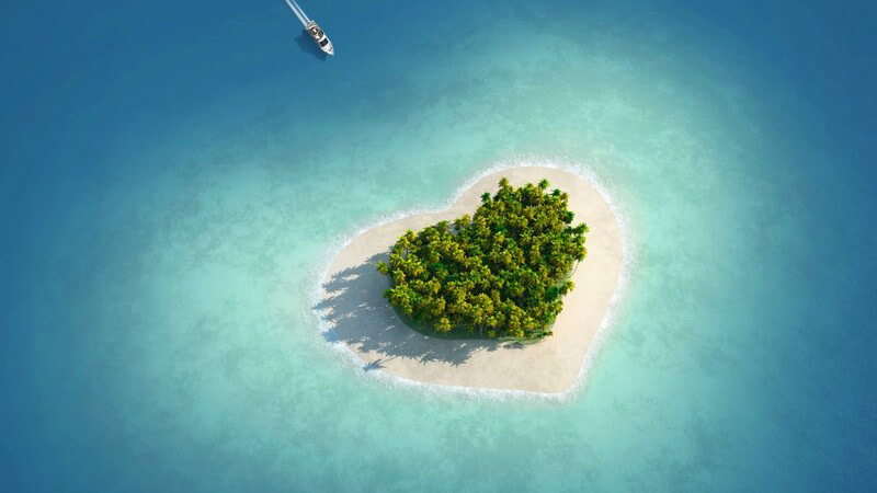 Winzige Insel in Form eines Herzens wird von einem Boot angefahren, Blick von oben