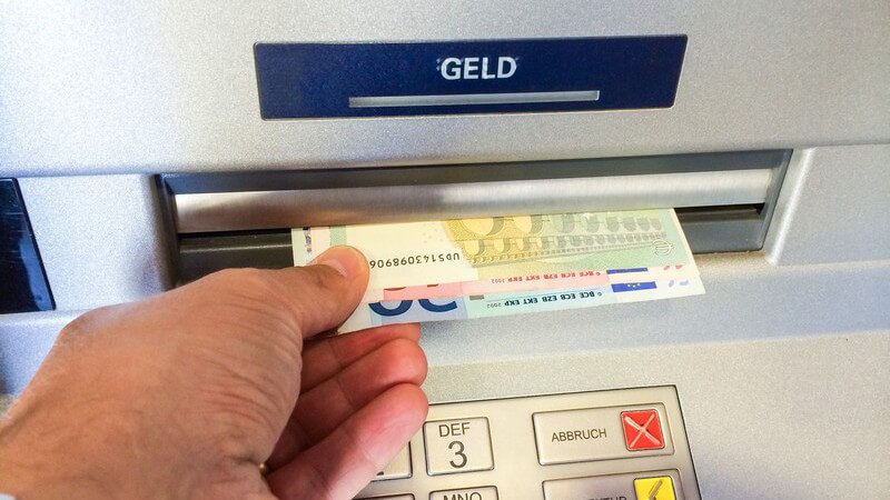 Mann nimmt Geldscheine aus einem Bankautomaten