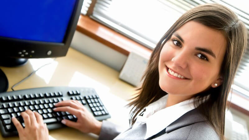 Junge Geschäftsfrau im Büro sitzt vor dem Computer