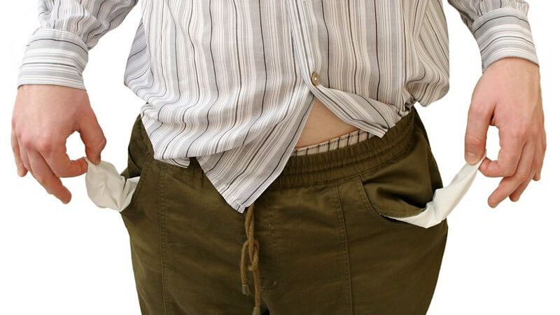Schulden - Mann mit dem Hemd aus der Hose zeigt seine leeren Hosentaschen
