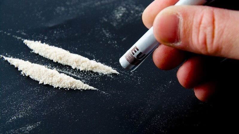 Drogen werden mit einem Geldschein in eine Linie geformt, Kokain
