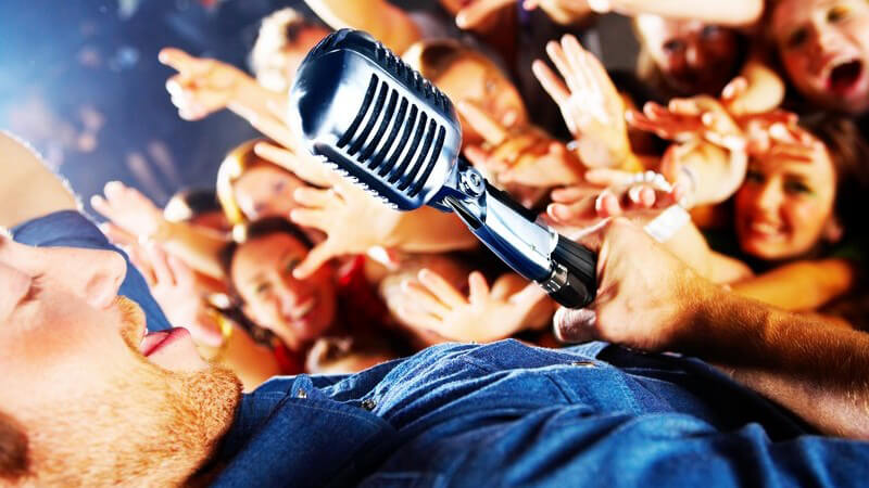 Sänger am Mikrofon wird von Mädchen in Menschenmenge bejubelt