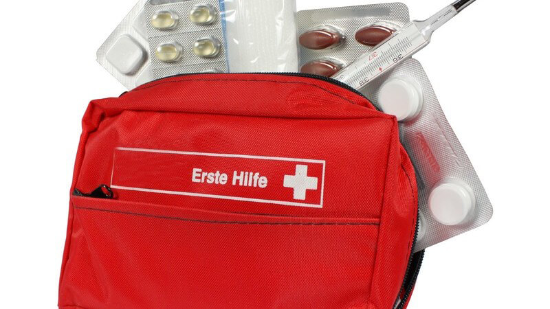 Rote Erste Hilfe-Tasche mit Fieberthermometer und Tabletten