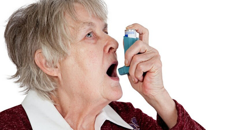 Ältere Frau benutzt Asthma-Inhalator
