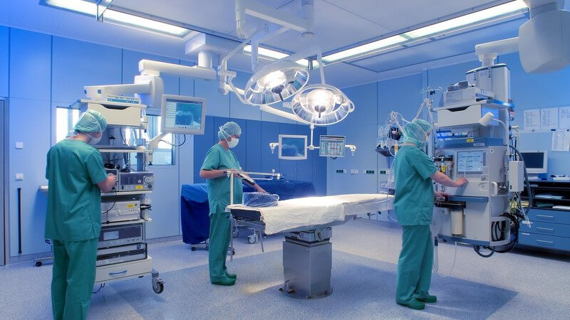 Chirurgen in grünen Kitteln und Mundschutz im Operationssaal