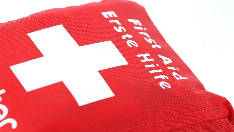 Roter Verbandskasten mit weißem Kreuz, "First Aid/Erste Hilfe"