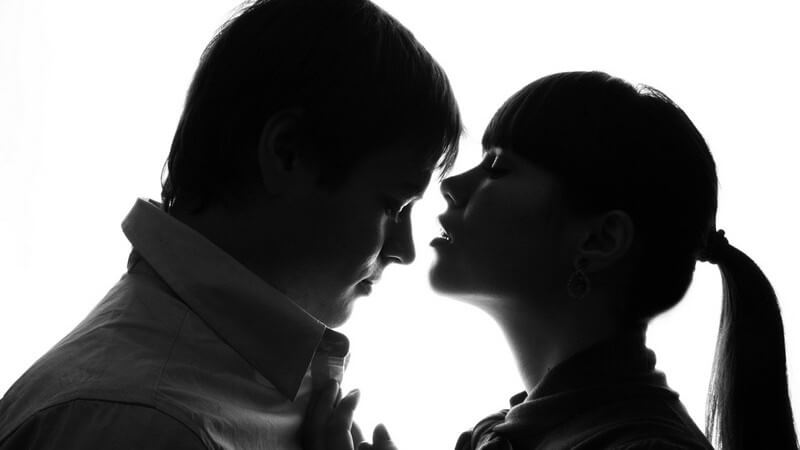Dunkel abgebildetes Paar sich zugewandt auf weißem Hintergrund
