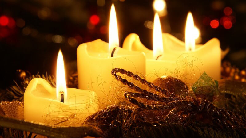 Adventskranz mit vier brennenden, gelben Kerzen