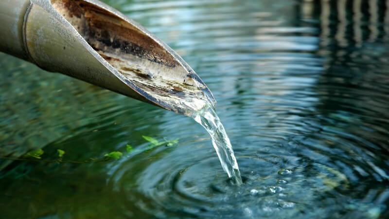 Wasser läuft aus Bambusrohr in Fluss