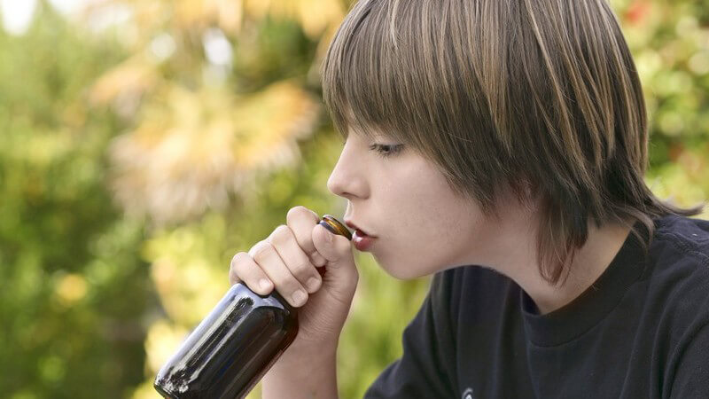 Jugendlicher setzt Bierflasche zum Trinken an