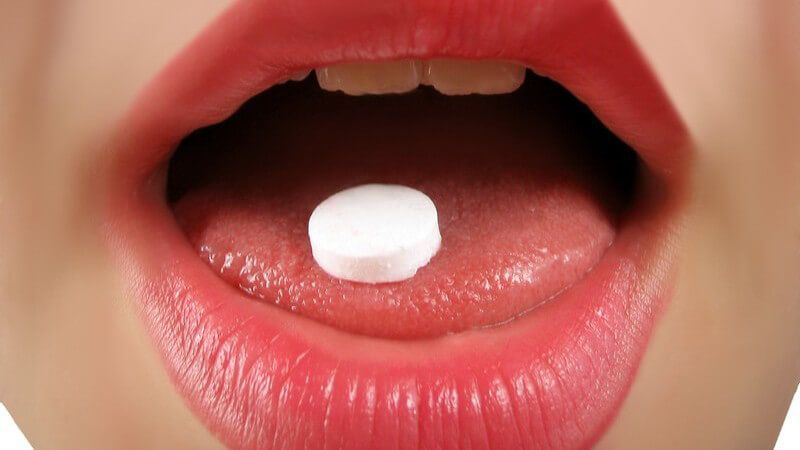 Roter Mund mit Pille auf der Zunge
