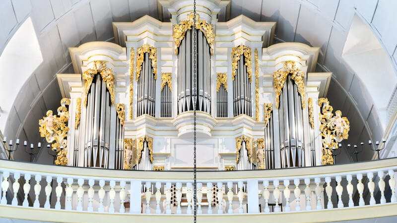 Blick auf die große weiße und goldverzierte Orgel in einer Kirche