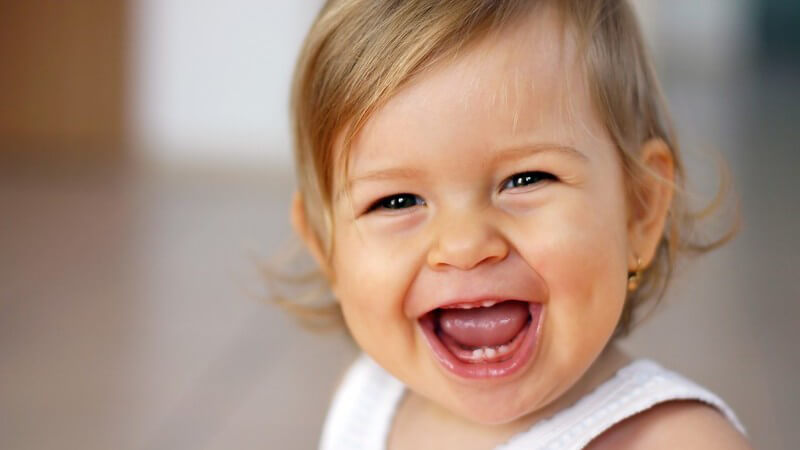 Lachendes Baby mit offenem Mund schaut in Kamera