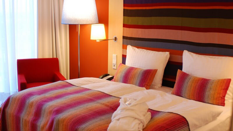 Doppelbett mit buntem Überwurf, Einsicht in ein Hotelzimmer