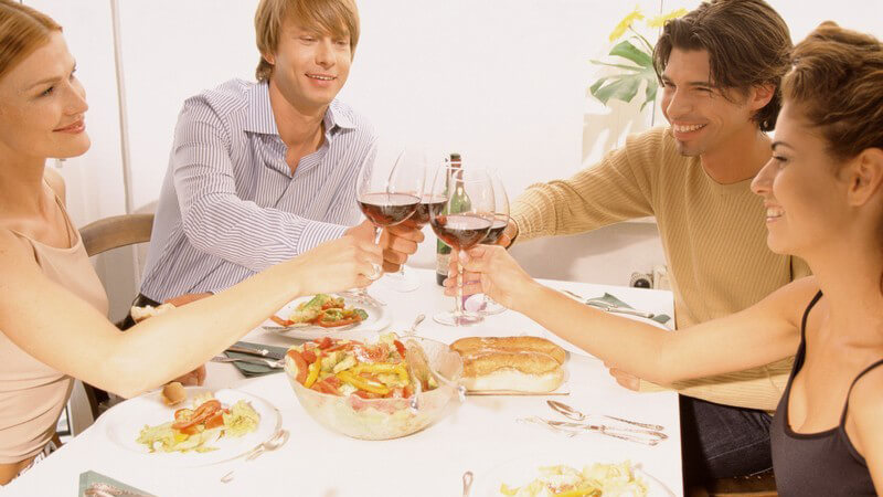 Vier Freunde stoßen bei einem Dinner mit Wein an
