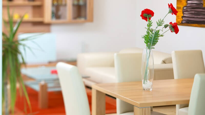 Rote Blumen in Vase auf Tisch im Ess-Wohnraum einer Wohnung