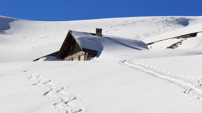 Verschneite Skihütte in Schneelandschaft mit Pisten