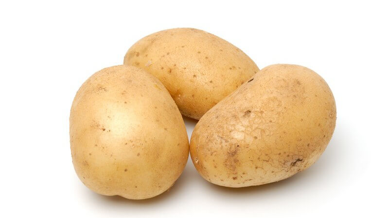 Drei ungeschälte rohe Kartoffeln auf weißem Hintergrund