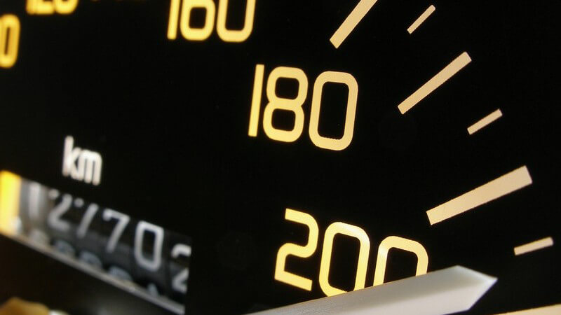 Schwarzer Tachometer mit gelben Zahlen, der weiße Zeiger zeigt auf 210