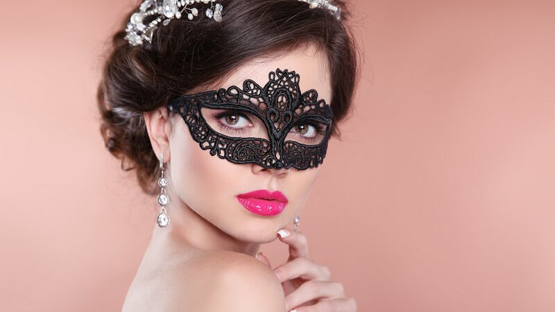 Portrait eines Models mit pinken Lippen, schwarzer Augenmaske und glamourösem Haarschmuck
