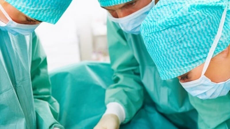 Operation - Drei Ärzte bei chirurgischem Eingriff am OP-Tisch
