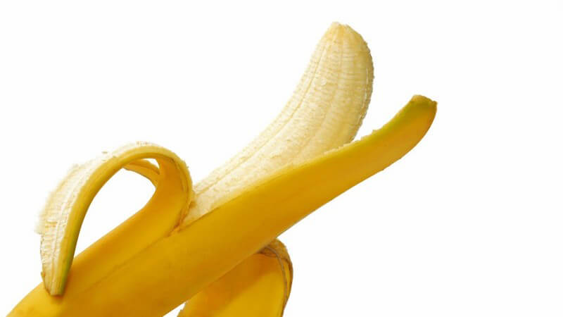 Nahaufnahme halb geschälte Banane auf weißem Hintergrund