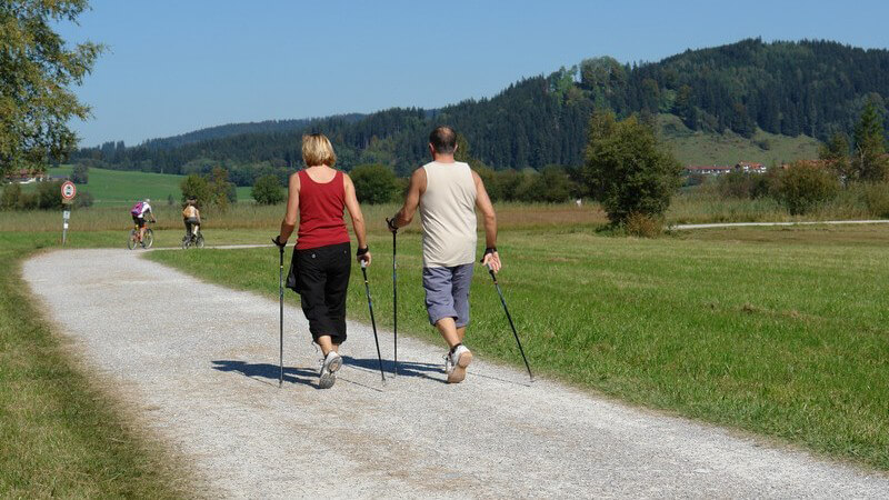 Rückansicht Paar beim Nordic Walking auf Feldweg