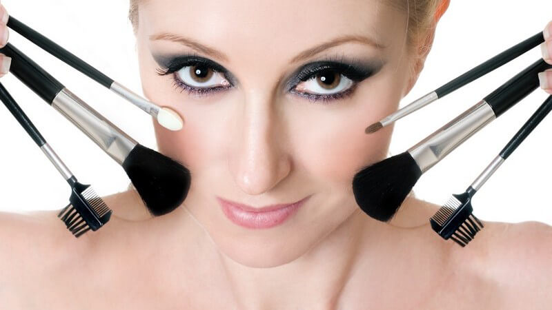 Geschminktes Frauengesicht, an den Seiten Make-up Pinsel und Applikatoren