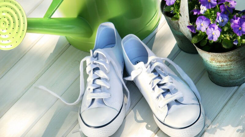 Weiße Schuhe vor Blumentöpfen und Gießkanne